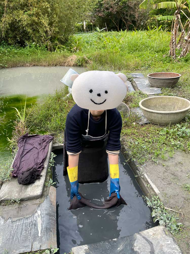 泥田で泥染をするくま子